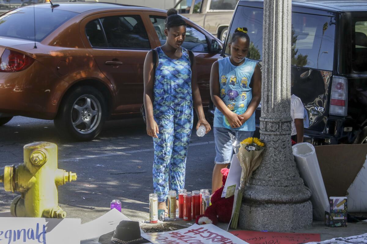 Patricia Thomas, 11, left, and Raquel Thomas, 9, pay their respects at a makeshift memorial for their father, Reginald Thomas, who died after being Tasered by Pasadena police.