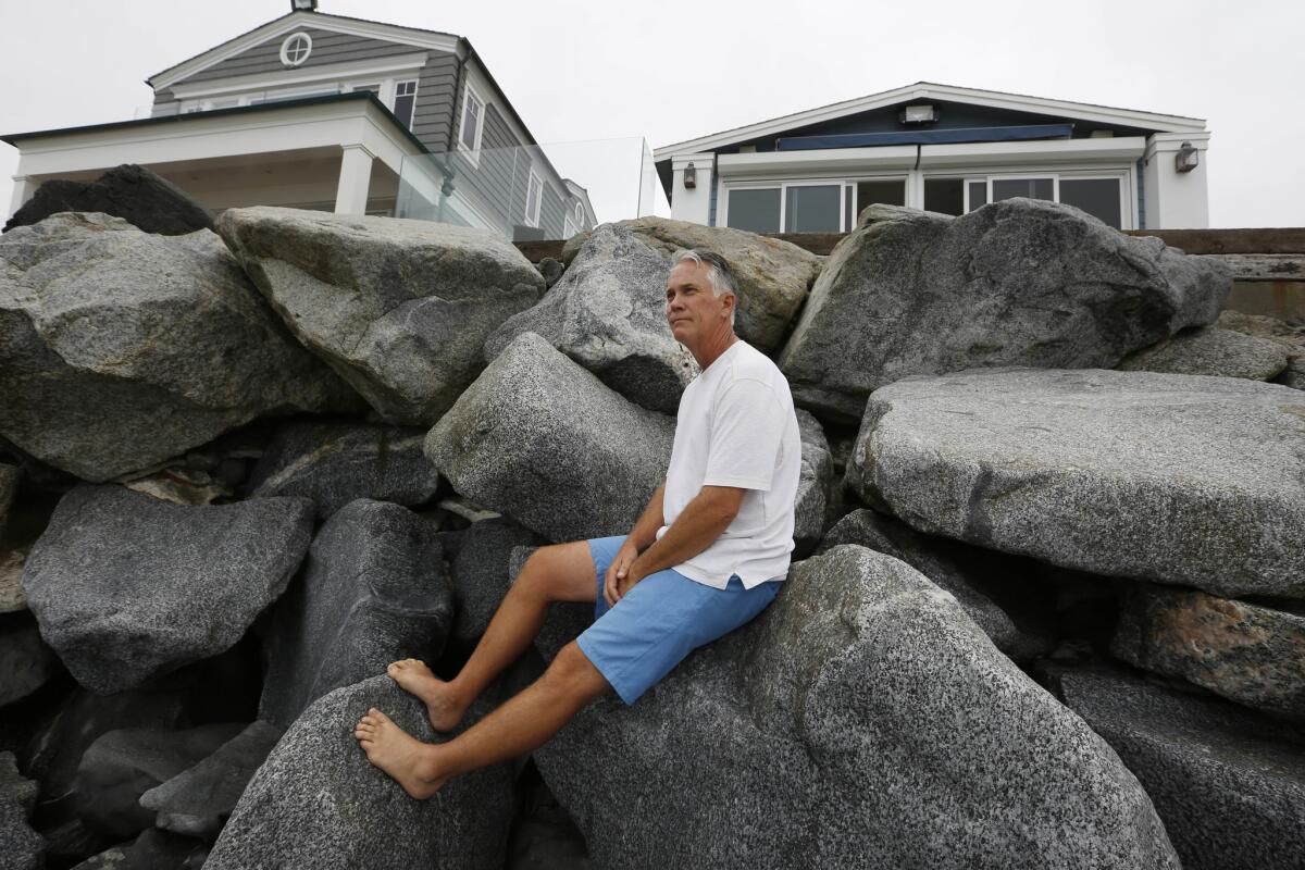 Eric Wills sits on the sea wall in front of his mobile home in Capistrano Shores.