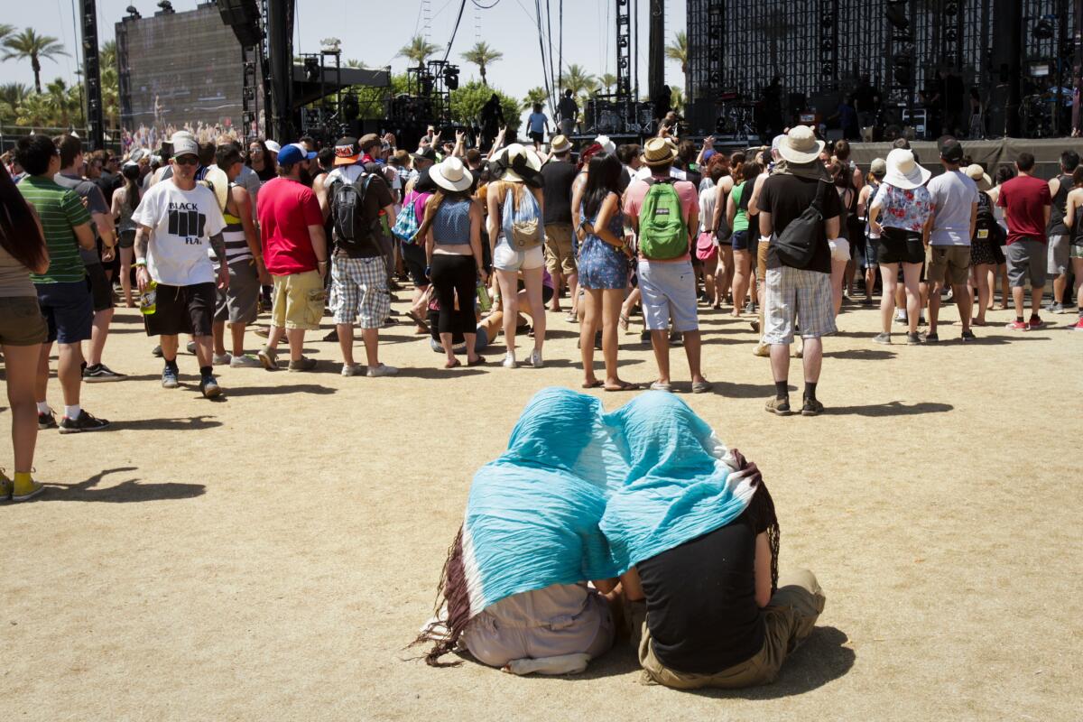 A pair of listeners shade themselves under a scarf while watching Ghost B.C. perform on the main stage during the last day of the second weekend of the Coachella Valley Music and Arts Festival.