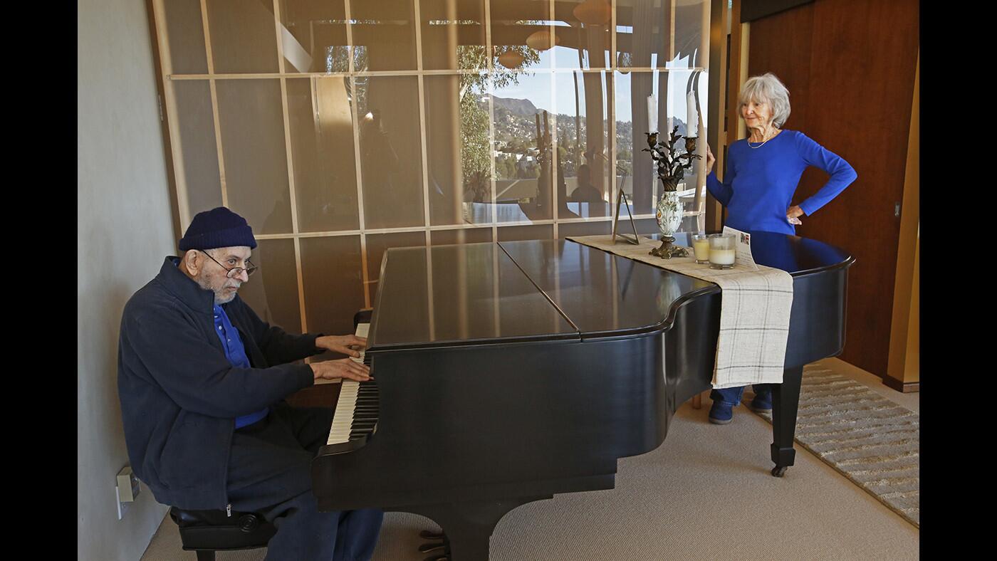 Herbert Bernard plays the piano in the living room as his wife Ileene Bernard listens.