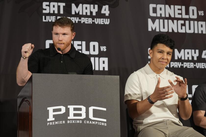 Undisputed super middleweight champion Canelo Alvarez, left, celebrates for Mexico with boxer Jaime Munguía during a news conference in Beverly Hills, Calif., Tuesday, March 19, 2024. Alvarez will defend his titles against All-Action Star Jaime Munguía on Saturday, May 4, at T-Mobile Area in Las Vegas. (AP Photo/Damian Dovarganes)