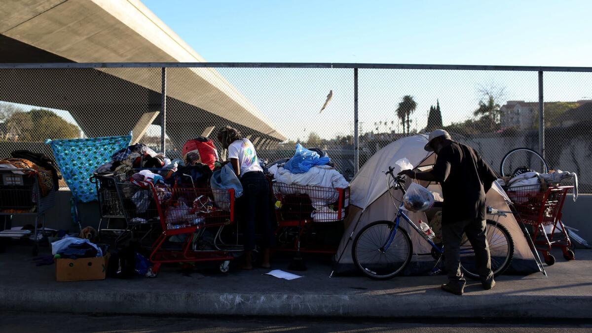 People stand outside their tents on the 42nd Street overpass over highway 110 in Los Angeles on Feb. 15, 2016.