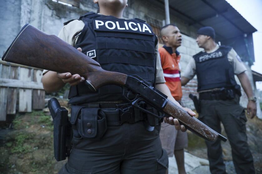 En esta imagen de archivo, un agente de policía hace guardia mientras una persona es detenida durante un registro en busca de armas o drogas, dentro de una operación para luchar contra las bandas criminales, en el vecindario de Nueva Guayaquil, en Guayaquil, Ecuador, el 4 de abril de 2024. (AP Foto/César Muñoz, archivo)