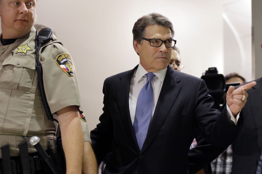 FILE - Texas Gov. Rick Perry, right, arrives at the Blackwell Thurman Criminal Justice Center for booking, in Austin, Texas, Aug. 19, 2014. Perry was facing abuse of power charges over a veto that prosecutors said he issued to settle political scores. The case against him never went to trial. (AP Photo/Eric Gay, File)