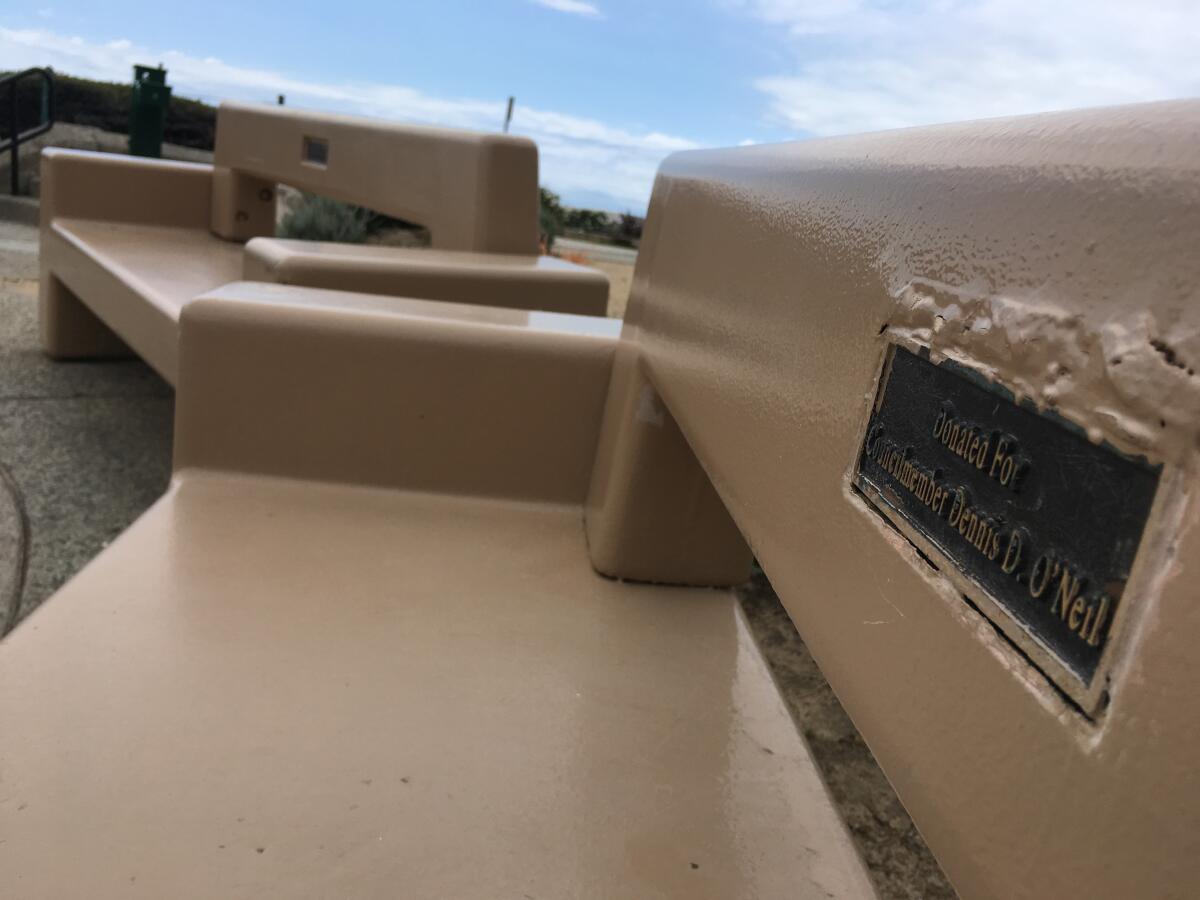 Two benches with names inscribed on tribute plaques sit on a bluff facing Little Corona del Mar Beach.
