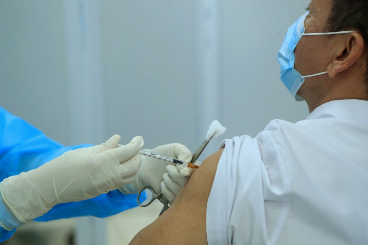 A health worker injects a doctor with a dose of AstraZeneca COVID-19 vaccine.