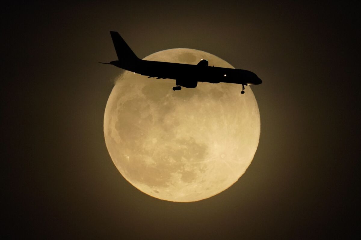 FILE - In this Monday, April 26, 2021 file photo, a jet is silhouetted by the rising moon as it approaches Louisville International Airport in Louisville, Ky. Air travel continues to recover from the pandemic, although it's still not close to normal. The Transportation Security Administration said that nearly 1.67 million people were screened at U.S. airport checkpoints on Sunday, May 2, 2021. (AP Photo/Charlie Riedel)