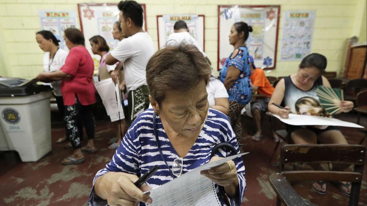 A Filipina checks her ballot as she votes at a polling center at the Manuel L. Quezon elementary school, Manila.