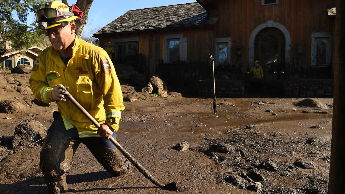 Firefighter Alex Jimenez wades through mud after using a stick to mark the spot where he found a body in Montecito.