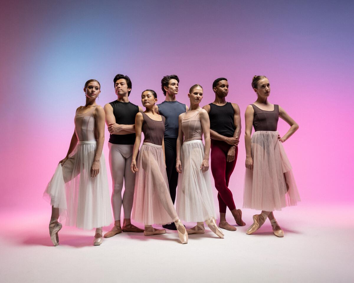 Male and female ballet dancers in long chiffon skirts pose for a portrait.