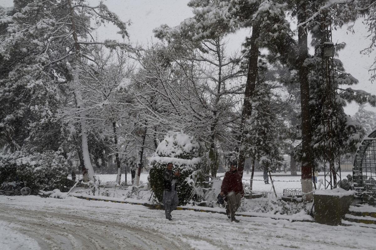 People walk along a road during heavy snowfall in Quetta, Pakistan, on Sunday.