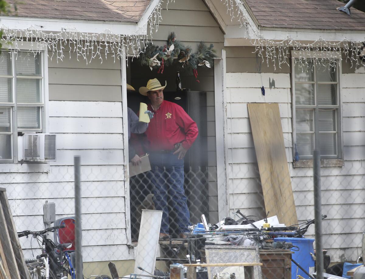 A Texas sheriff stands in the doorway of a house.