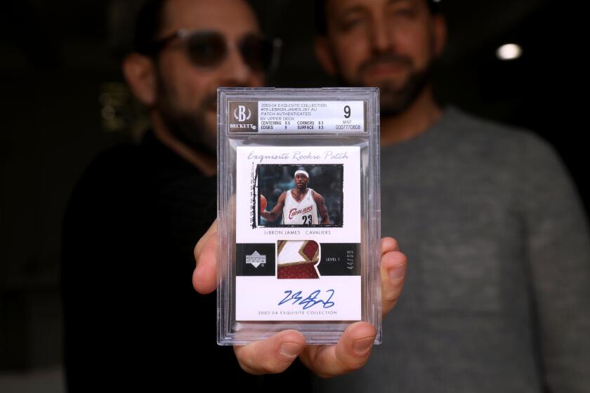 VALLEY VILLAGE, CA - JANUARY 17, 2024 - - Steven Spiegel, left, next to his brother Alan, holds a LeBron James rookie card valued at about $1 million at his home in Valley Village on January 17, 2024. The Spiegel brothers are co-owners of the card. The 2003-2004 card, which has Lebron's autograph on it and a swatch of his jersey, is the subject of litigation - the Spiegel's allege that Goldin Auctions breached a contract to auction the card in 2022. The card was pulled from a Goldin auction after online chatter from a shadowy Instagram account called "Card Porn" cast doubt on the special rookie card's authenticity. The Spiegel's have sought damages from Goldin, which is led by high-profile card industry player Ken Goldin, and say their lawsuit is about making the hobby safe for kids. (Genaro Molina/Los Angeles Times)