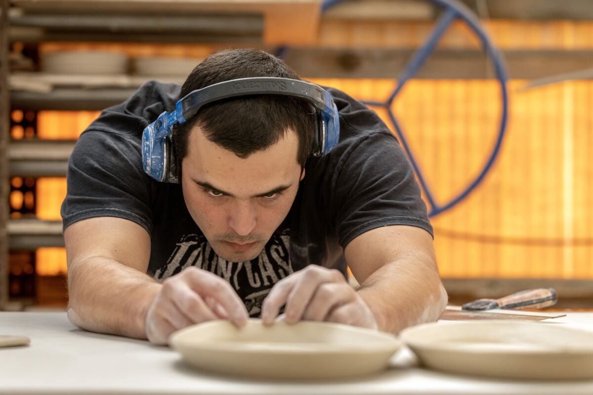 Mat Gibbons inspects a platter he just folded into shape. He's one of 10 employees who work at The Wheel.