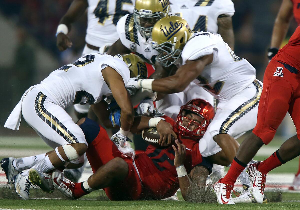 Wildcats qurterback Anu Solomon is brought down hard by Bruins defenders, resulting in an injury that took him out of the game last in the first half.