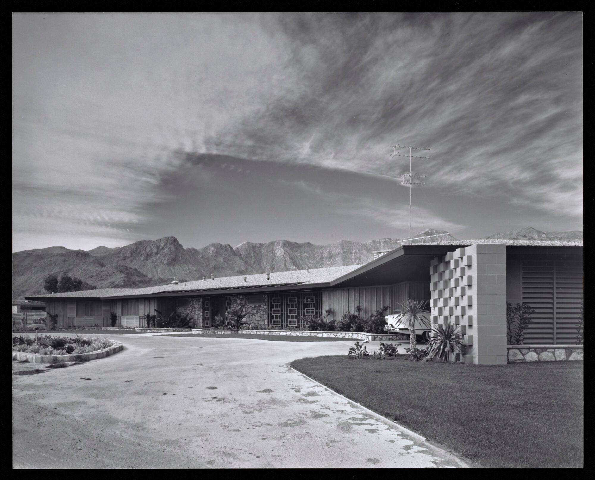 A black-and-white photo shows a low-slung Modern home with the San Jacinto Mountains in the distance.