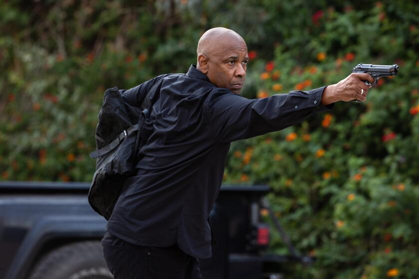 Denzel Washington wearing all black and pointing a gun