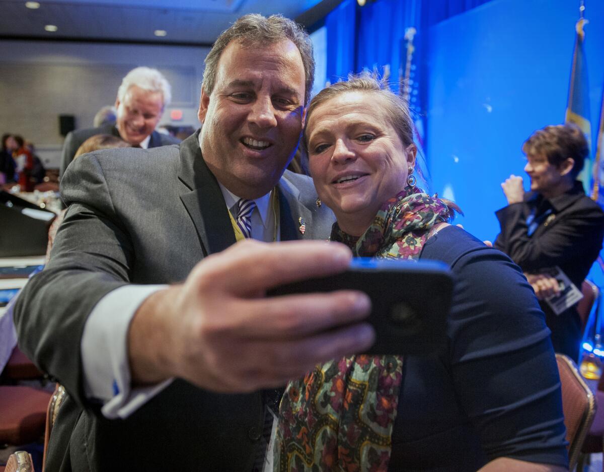 New Jersey Gov. Chris Christie takes a cellphone photo with National Governors Assn. staffer Lily Kersh of Little Rock, Ark., during the group's winter meeting in Washington