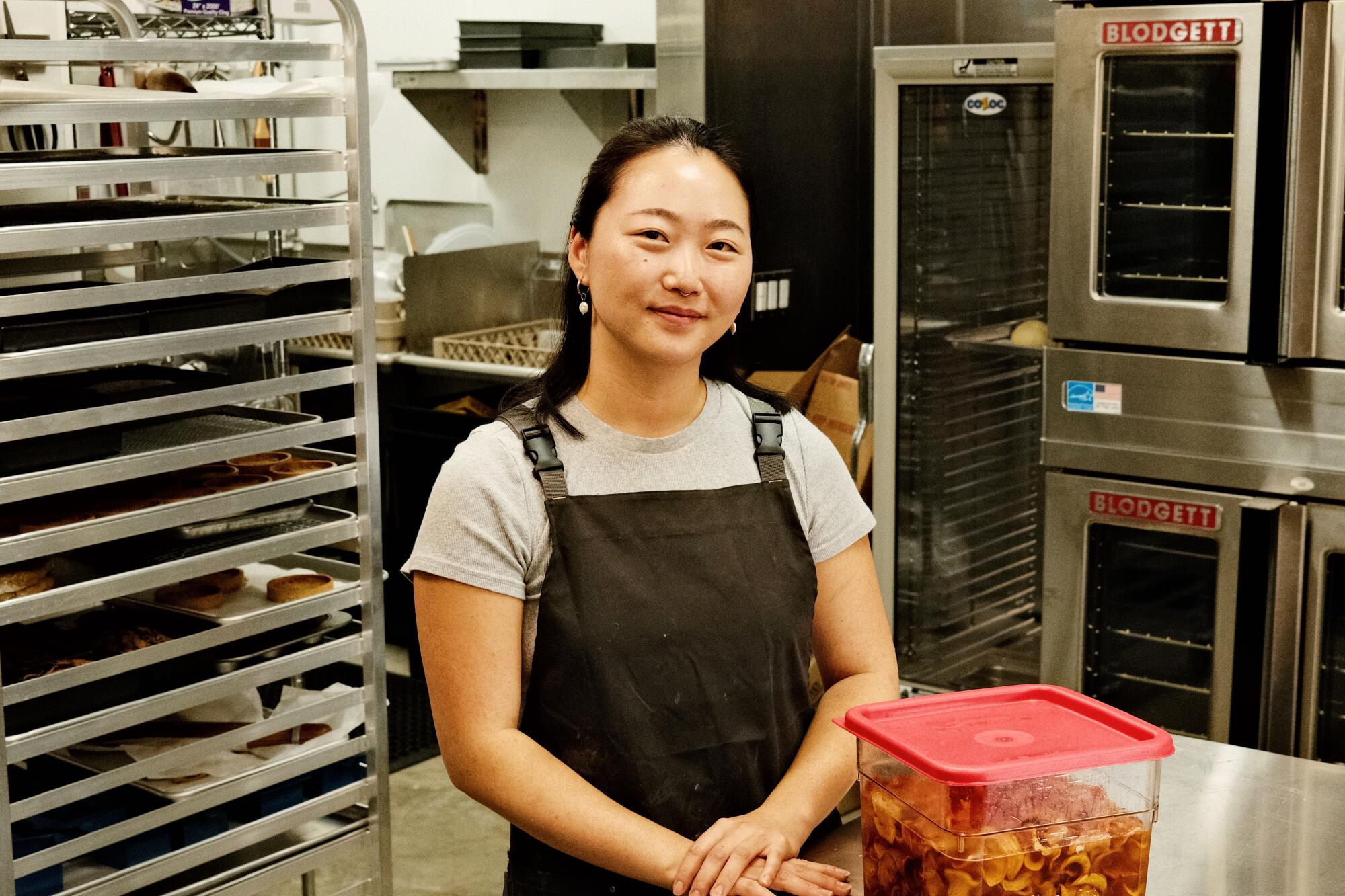 Jiyoon Jang stands with a container of rice-soaked persimmons in the kitchen of Modu, her Highland Park cafe.