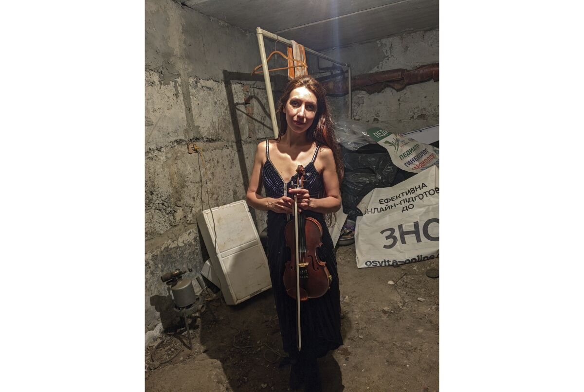 In this photo provided by violinist Vera Lytovchenko, she stands in a cellar with her violin in Kharkiv, Ukraine, on March 4, 2022. She performs in a new online video called "The Brave Ones" with other artists from various nations, including the U.S., South Africa, Japan and Canada, to raise money for humanitarian aid for musicians in Ukraine. (Vera Lytovchenko via AP)