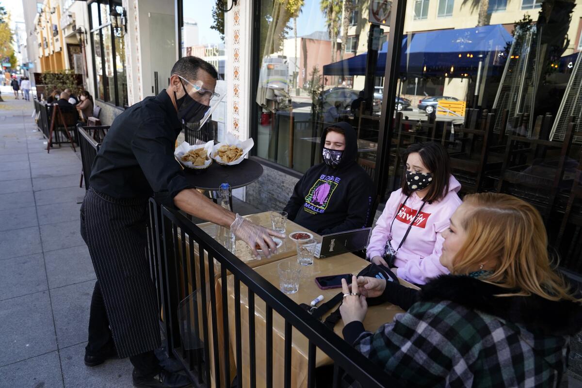 FILE - In this Tuesday, Dec. 1, 2020, file photo, customers are served lunch at an outdoor seating space in Pasadena, Calif. The nation's largest county acted "arbitrarily" when it banned outdoor dining at restaurants during the coronavirus pandemic, a Los Angeles judge tentatively ruled Tuesday, Dec. 8, 2020, in a case that could have implications for other California businesses struggling during the state shutdown. (AP Photo/Marcio Jose Sanchez, File)