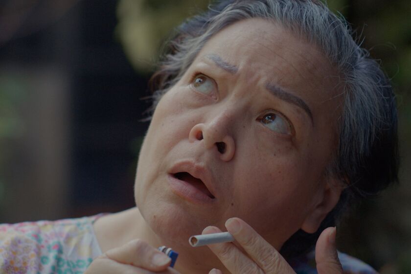 A woman holding an unlit cigarette and looking upward in the movie "Leonor Will Never Die."