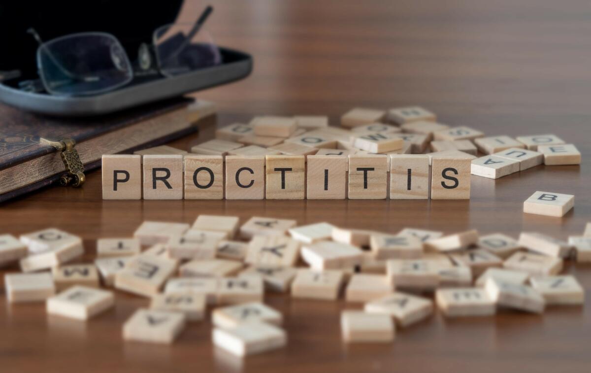 Proctitis word or concept represented by wooden letter tiles on a wooden table with glasses and a book.