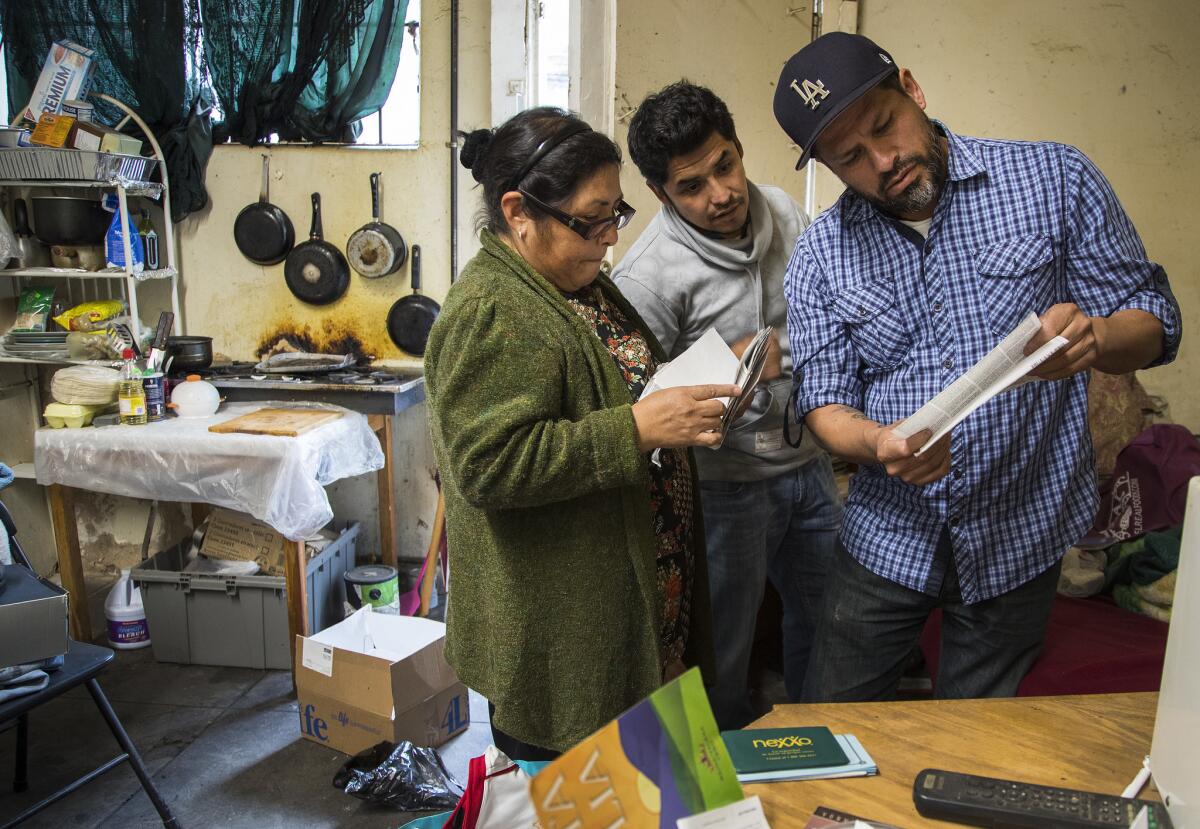 Cecilia Rebeca Chavez goes through Eduardo Hernandez’s belongings after his death with son Alfredo, center, and Luis Valentan, director of the Pasadena Community Job Center. (Gina Ferazzi / Los Angeles Times)