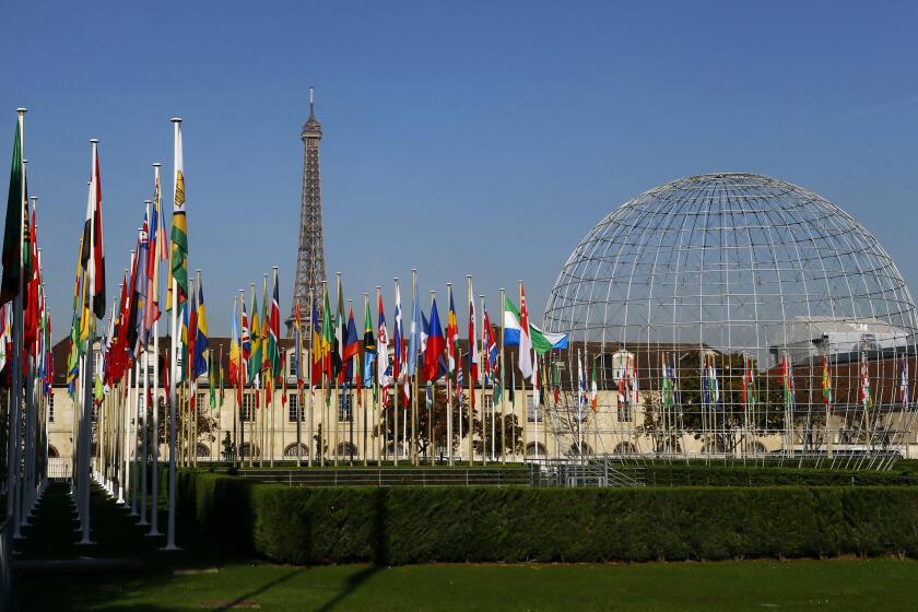 FILE - The Eiffel Tower, country flags and the Dome are seen from the garden of the United Nations Educational, Scientific and Cultural Organisation (UNESCO) headquarters building during the 39th session of the General Conference at the UNESCO headquarters in Paris. The United States is ready to rejoin the U.N. cultural and scientific agency UNESCO – and pay more than $600 million in back dues -- after a decade-long dispute sparked by the organization's move to include Palestine as a member. (AP Photo/Francois Mori, File)