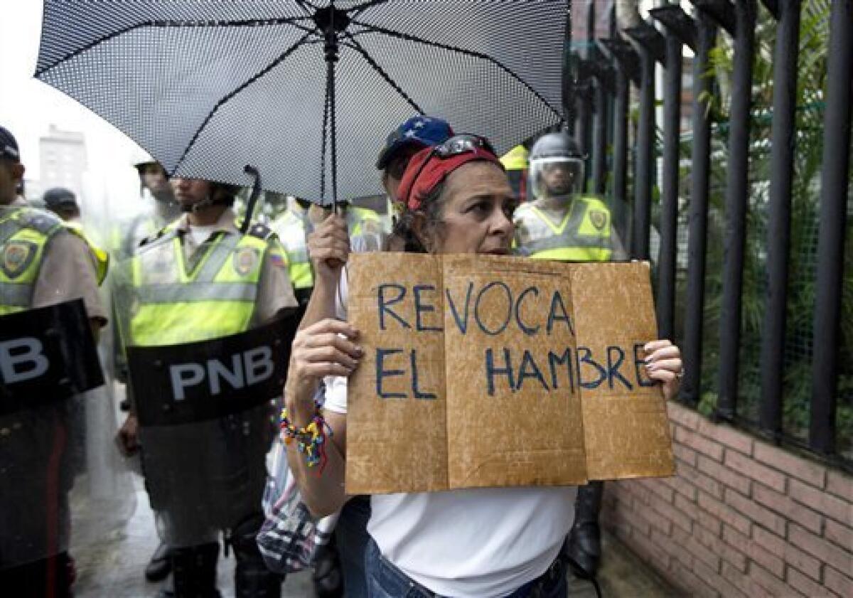 Una mujer sostiene un letrero durante una marcha de protesta de la oposición en Caracas,, la crisis económica ha dejado a los revendedores como los ganadores de la crisis económica.