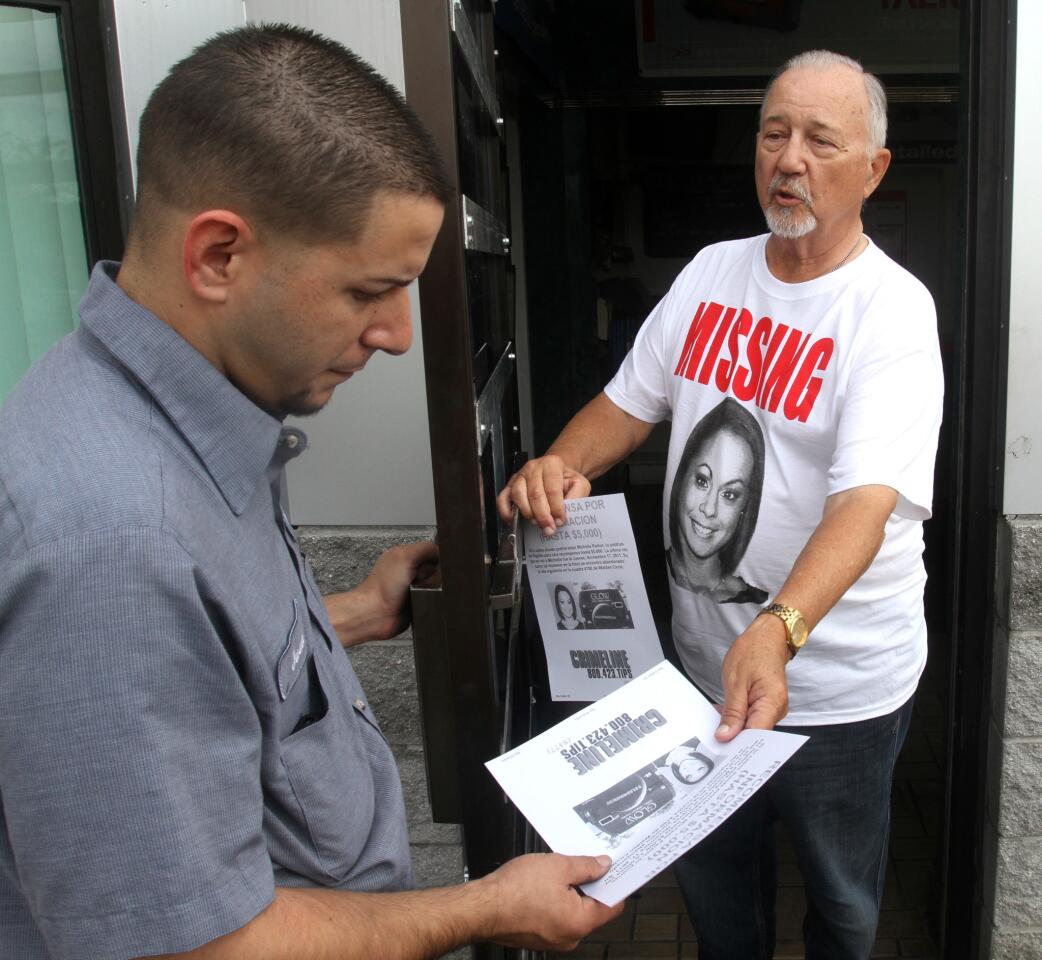 Volunteer Bill Dowell hands Texaco mechanic Juan Robles a poster, on Orange Blossom Trail in Orlando, Tuesday, Nov. 22, 2011, while distributing posters of Michelle Parker, who is the mother of three missing since last week.