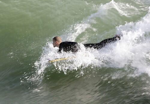 A surfer catches a wave next to the Port Hueneme pier.