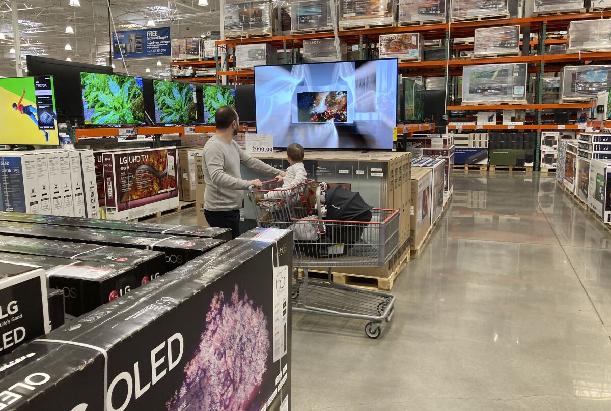 FILE - A shopper pushes a child in a cart while browsing big-screen televisions on display in the electronics section of a Costco warehouse, Tuesday, March 29, 2022, in Lone Tree, Colo. U.S. retail sales rose 0.9% in April, a solid increase that underscores Americans’ ability to keep ramping up spending even as inflation persists at nearly a 40-year high. The Commerce Department said Tuesday, May 17, that the increase was driven by greater sales of cars, electronics, and at restaurants. Even adjusting for inflation, which was 0.3% on a monthly basis in April, sales increased. (AP Photo/David Zalubowski, File)