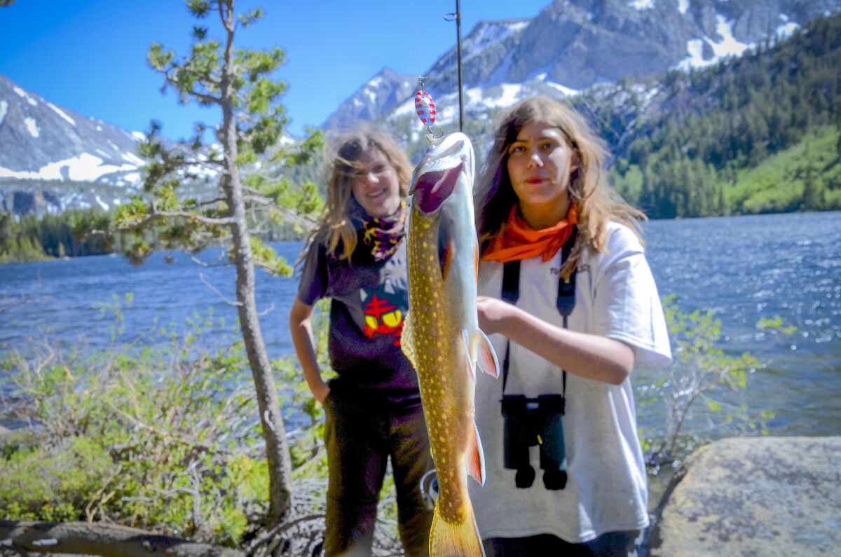 Olivia Palermo, 16, right, lands a trout at Davis Lake in the Eastern Sierra with her friends Kami Decker looking on. (Cristopher Reynolds / Los Angeles Times)
