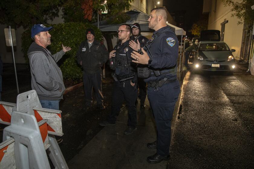 REDDING, CA-NOVEMBER 8, 2022: Richard Gallardo, left, a candidate for the Shasta County Board of Education, is told by members of the Redding police dept. that he is not allowed to walk into an alley to observe ballots being delivered to the Shasta County Clerk & Elections office in Redding because a temporary permit was obtained closing off the alley to members of the public. (Mel Melcon / Los Angeles Times)