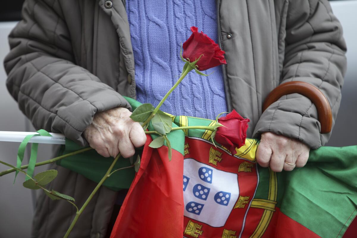 A Socialist Party supporter holds roses and a Portuguese flag