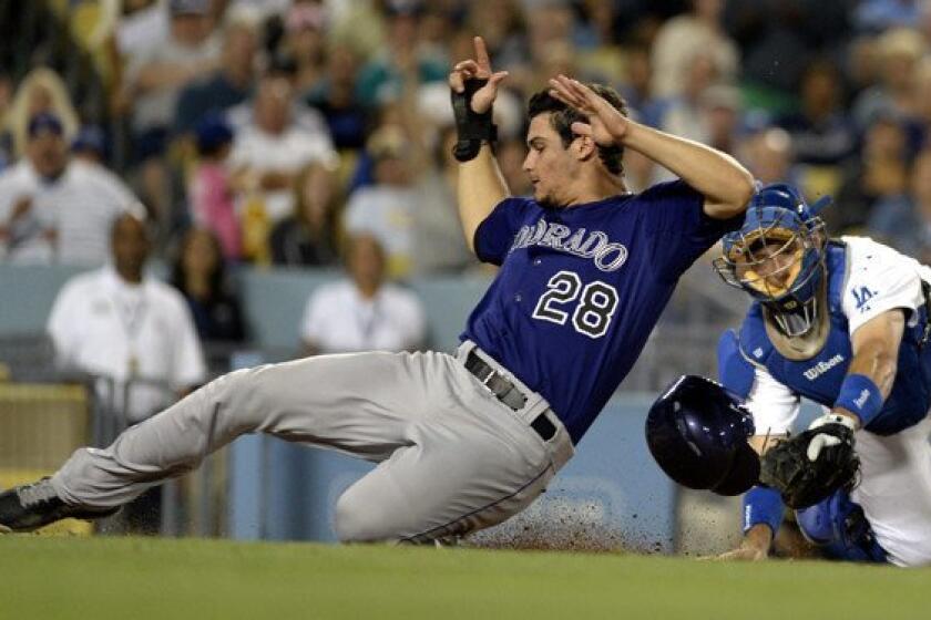 Rockies third baseman Nolan Arenado beats the tag by Dodgers catcher A.J. Ellis to score a run on a hit by D.J. LeMahieu in the fifth inning Friday night at Dodger Stadium.