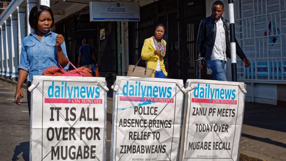 Pedestrians pass a newspaper stand on a street in downtown Harare, Zimbabwe, on Nov. 19.