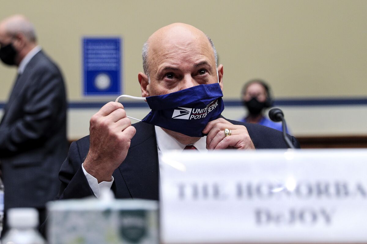 Postmaster General Louis DeJoy removes his  mask as he arrives to testify on Capitol Hill