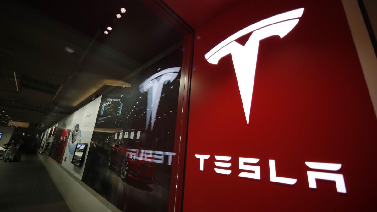 A sign bearing the Tesla logo is displayed outside its store in Cherry Creek Mall in Denver in February.