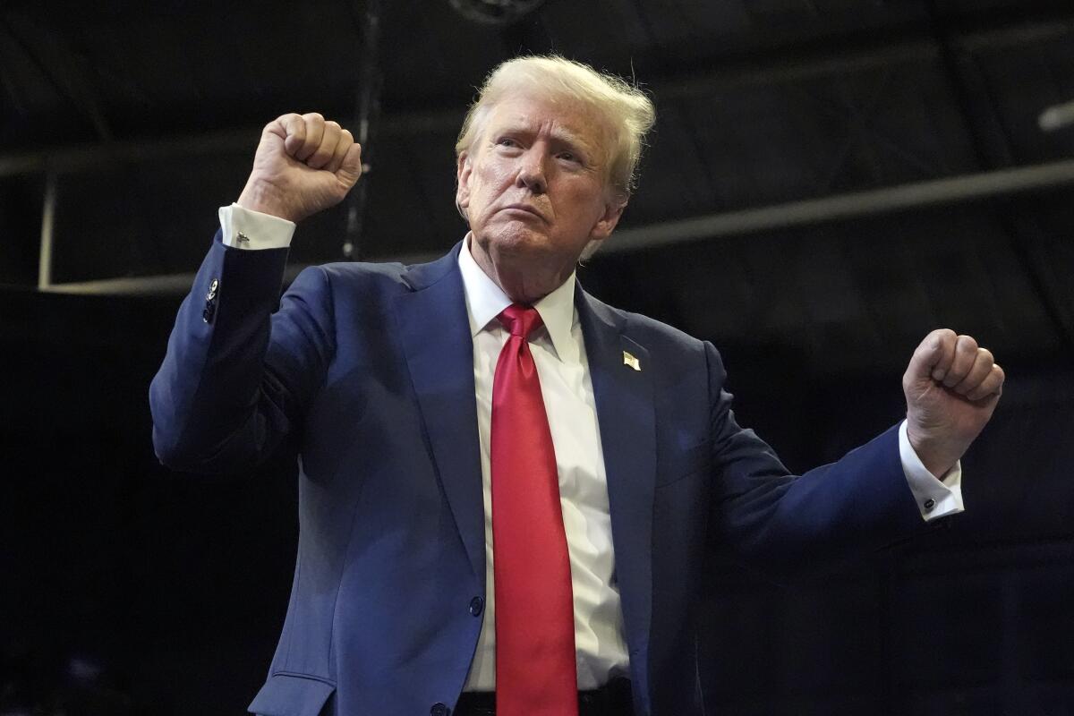 A man in a suit with a red tie and raised fists 