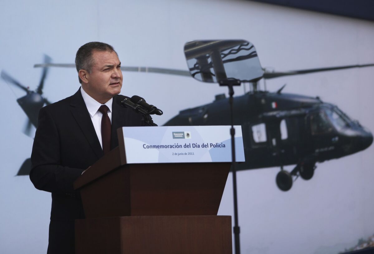 A man speaks on a platform in front of a picture of a helicopter. 