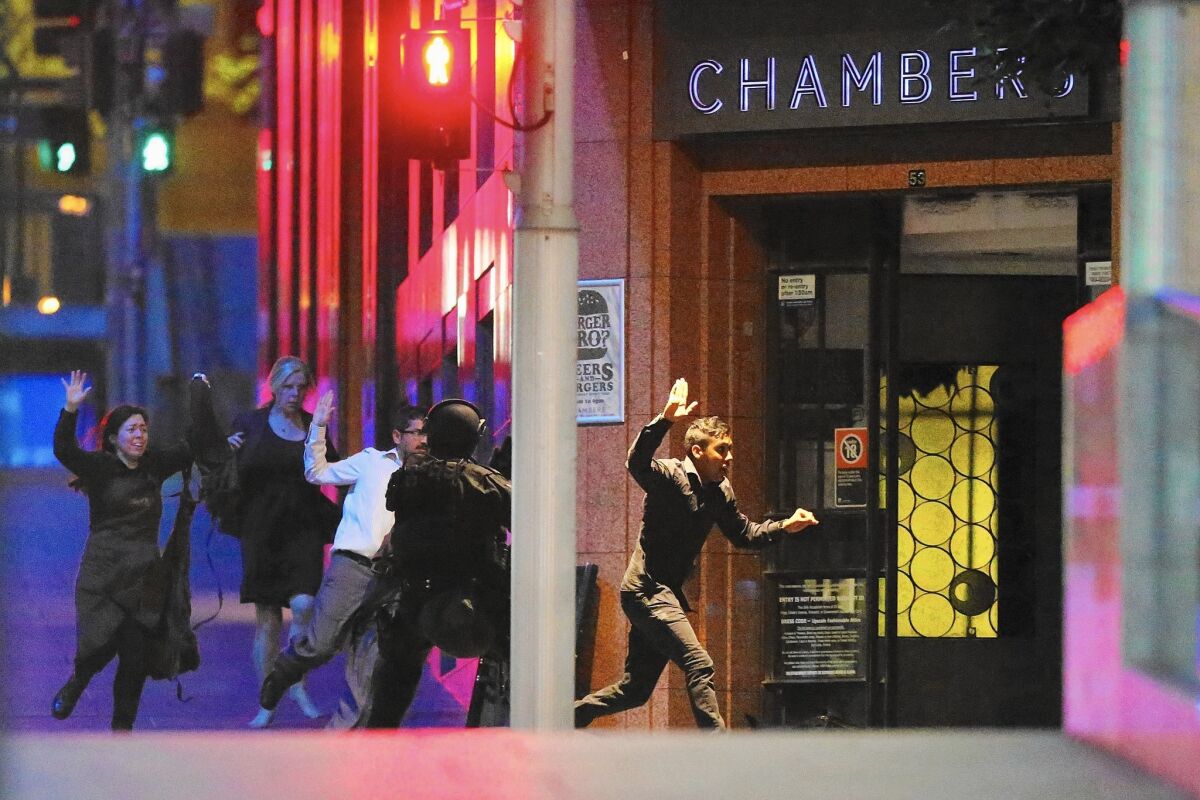 People run from the Lindt Chocolat Cafe in Sydney, Australia. Police said they stormed the cafe after hearing gunshots from inside.