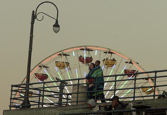 A couple look out from the Santa Monica Pier as sunset approaches. In honor of its centennial, the pier will host a fireworks show Sept. 9, the first over Santa Monica Bay since 1991.