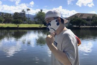 Ricardo Lay wears an aloha print mask, walks in the Waikiki neighborhood of Honolulu on April 7, 2020. 