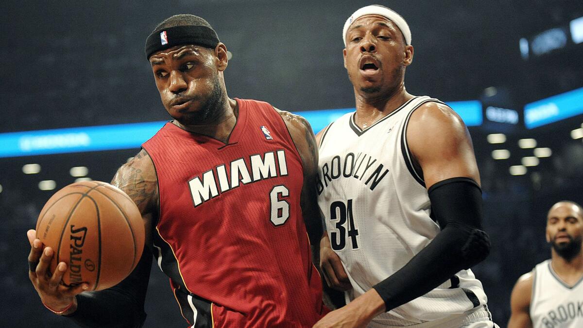 Miami Heat forward LeBron James grabs a rebound in front of Brooklyn Nets forward Paul Pierce during the first half of Miami's win Monday.