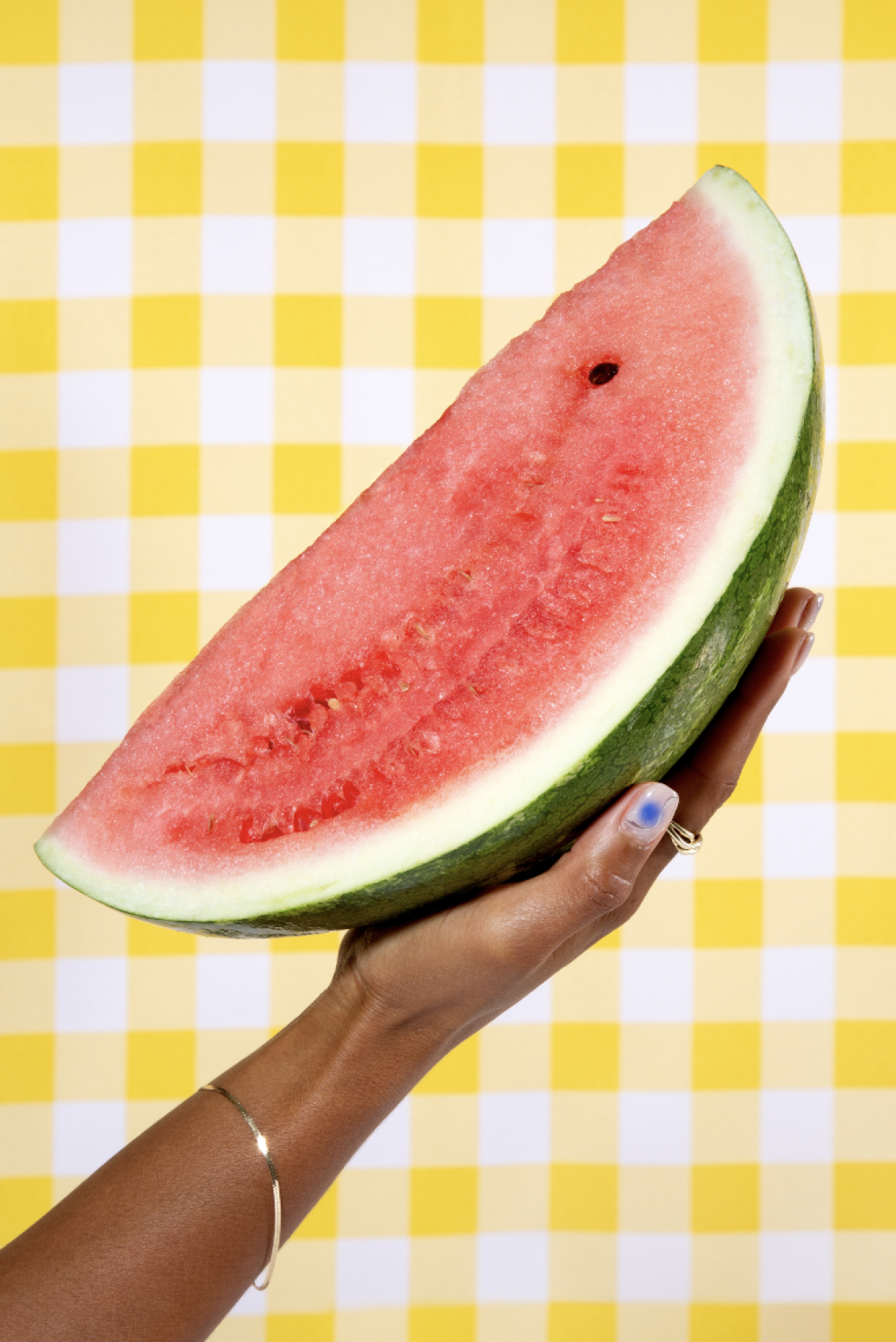 A hand holds up a large wedge of watermelon