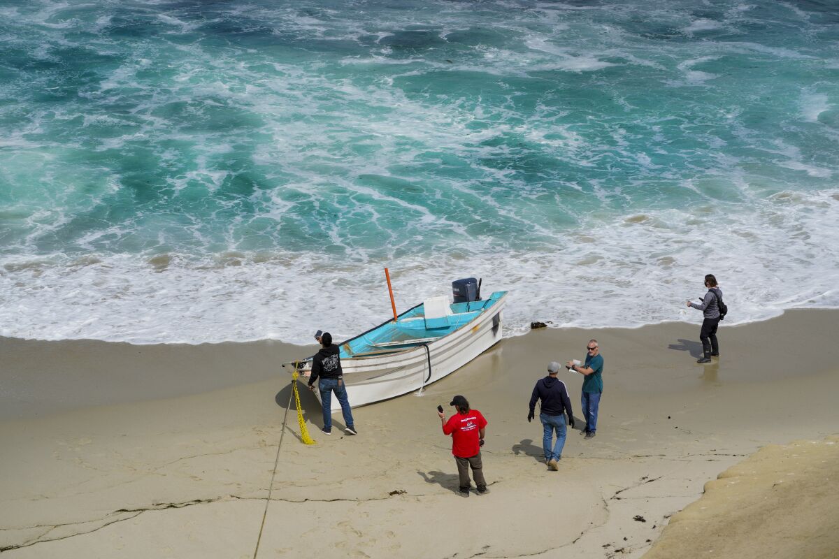 Investigators in La Jolla look over a small boat following what authorities say was a migrant smuggling attempt.