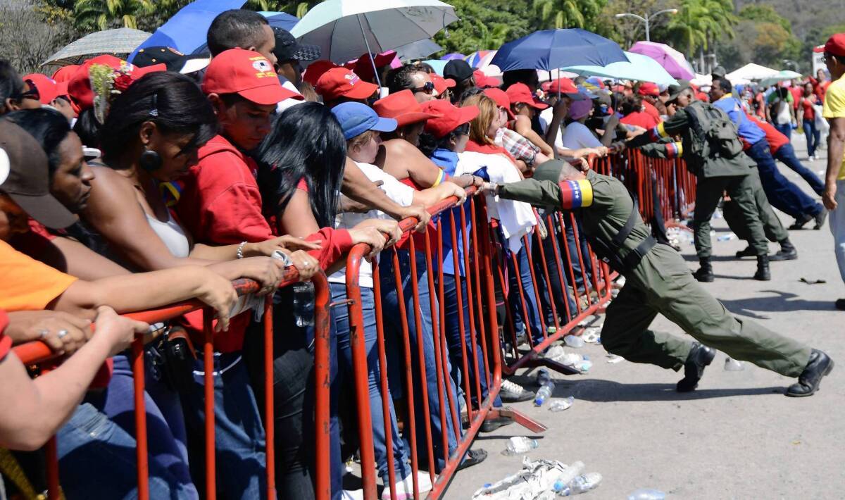 Venezuelan soldiers push the protective fences as supporters wait in line to pay their respects to Venezuelan President Hugo Chavez in Caracas on Thursday. The leader, 58, died of cancer on Tuesday.