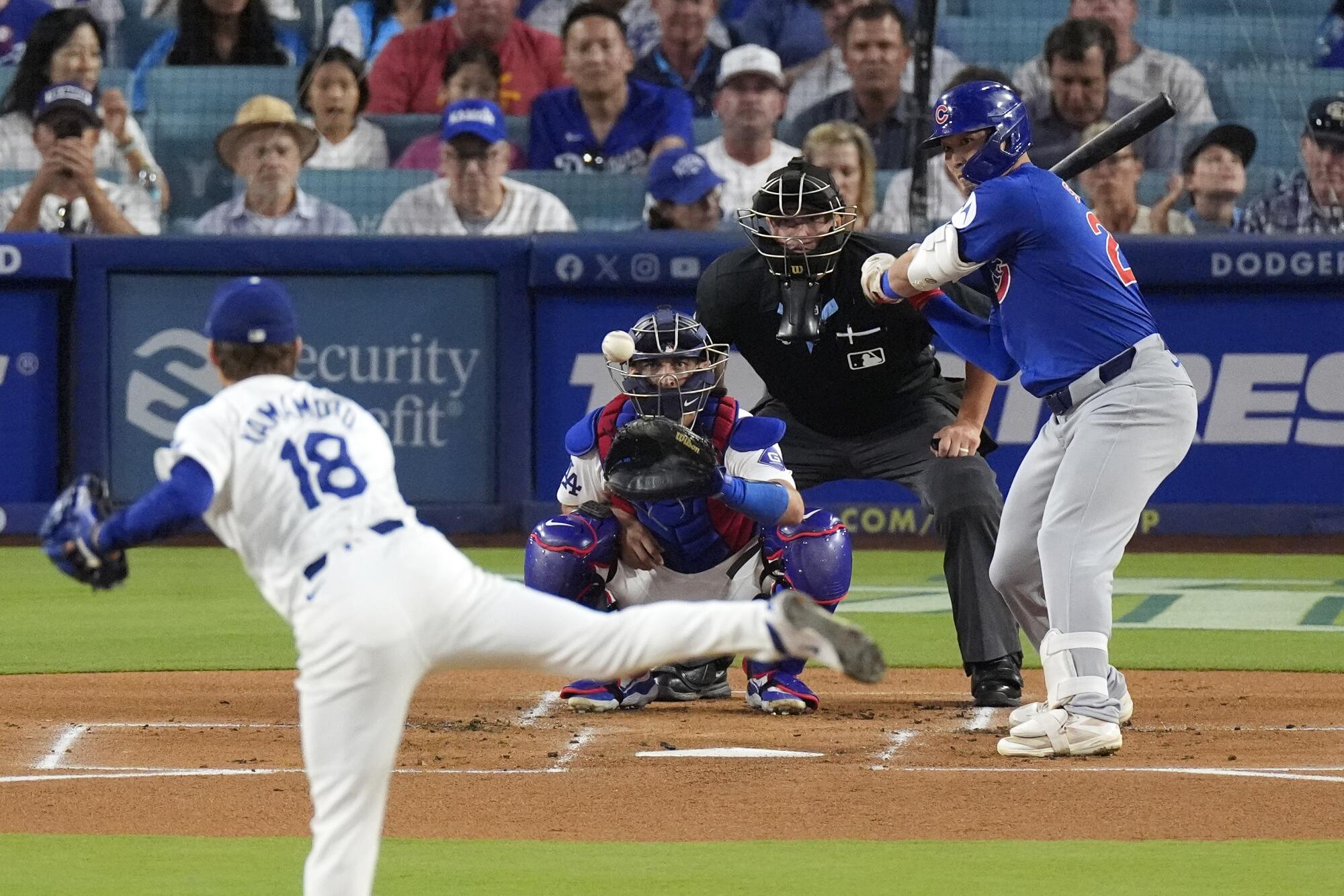 Yoshinobu Yamamoto pitches to Seiya Suzuki as catcher Austin Barnes and umpire Cory Blaser watch.